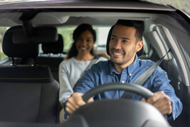 Happy Latin American driver transporting a woman in a car while talking to her - transportation concepts