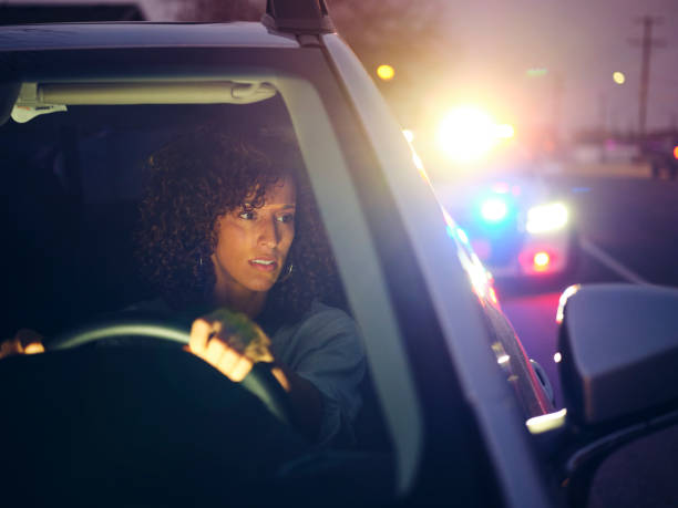 A young woman, being stopped by police at night for a traffic violation.